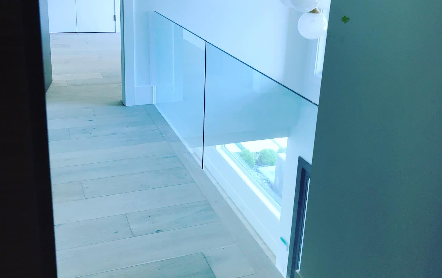 A hallway with a glass railing and a window.
