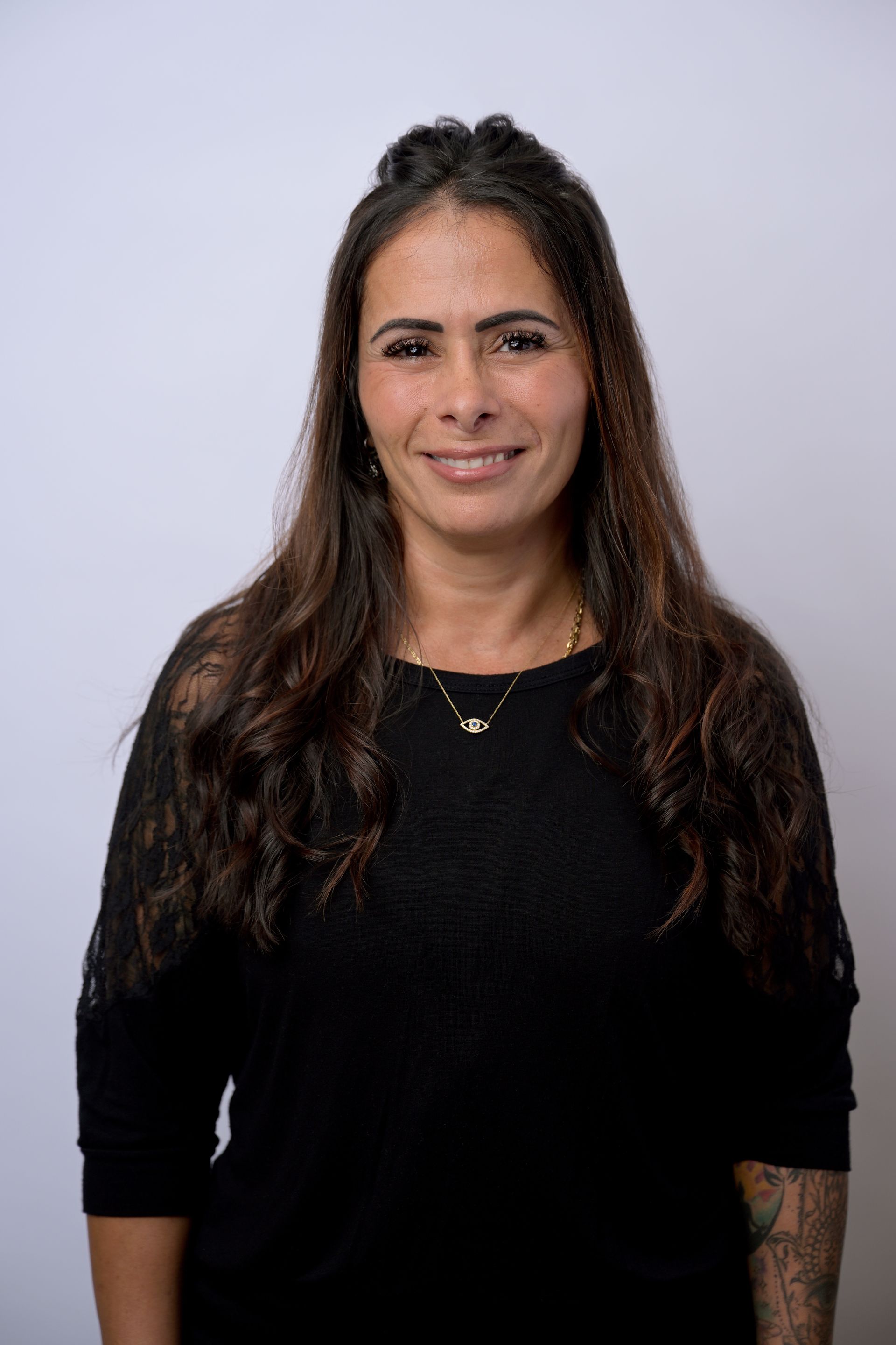 Two medical professionals, smiling, walking in a hospital hallway. One wears a white coat, the other blue scrubs, both have lanyards.