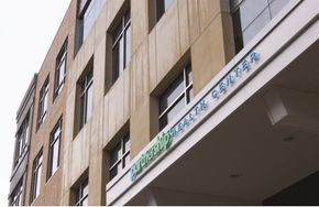 Exterior of a tan building with windows, the name