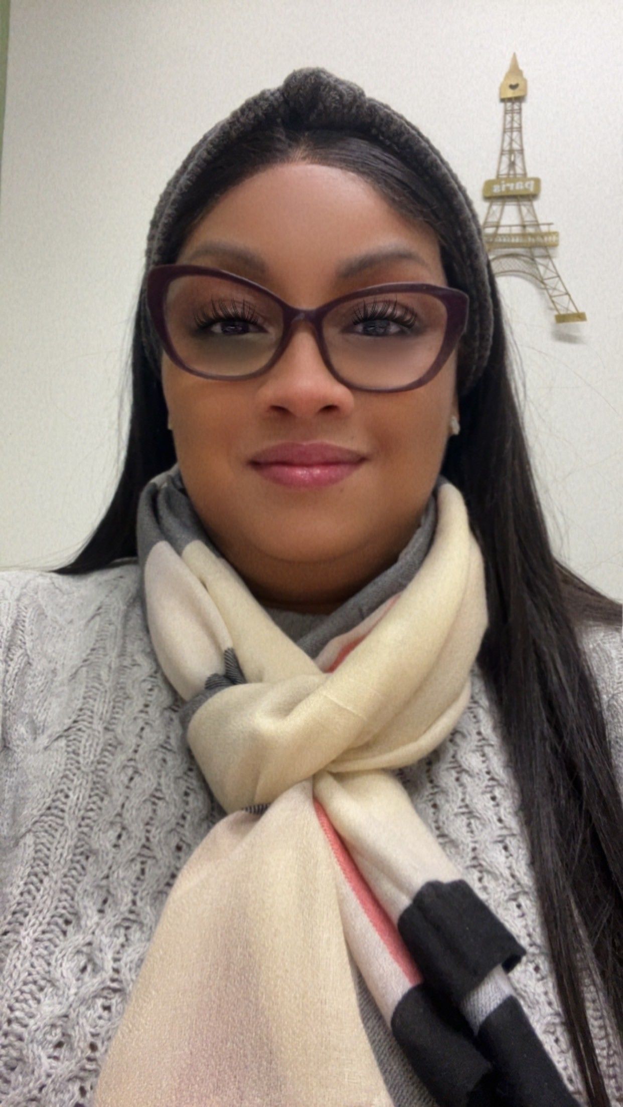 Woman in white uniform smiling, wearing a badge, near an emergency services emblem.