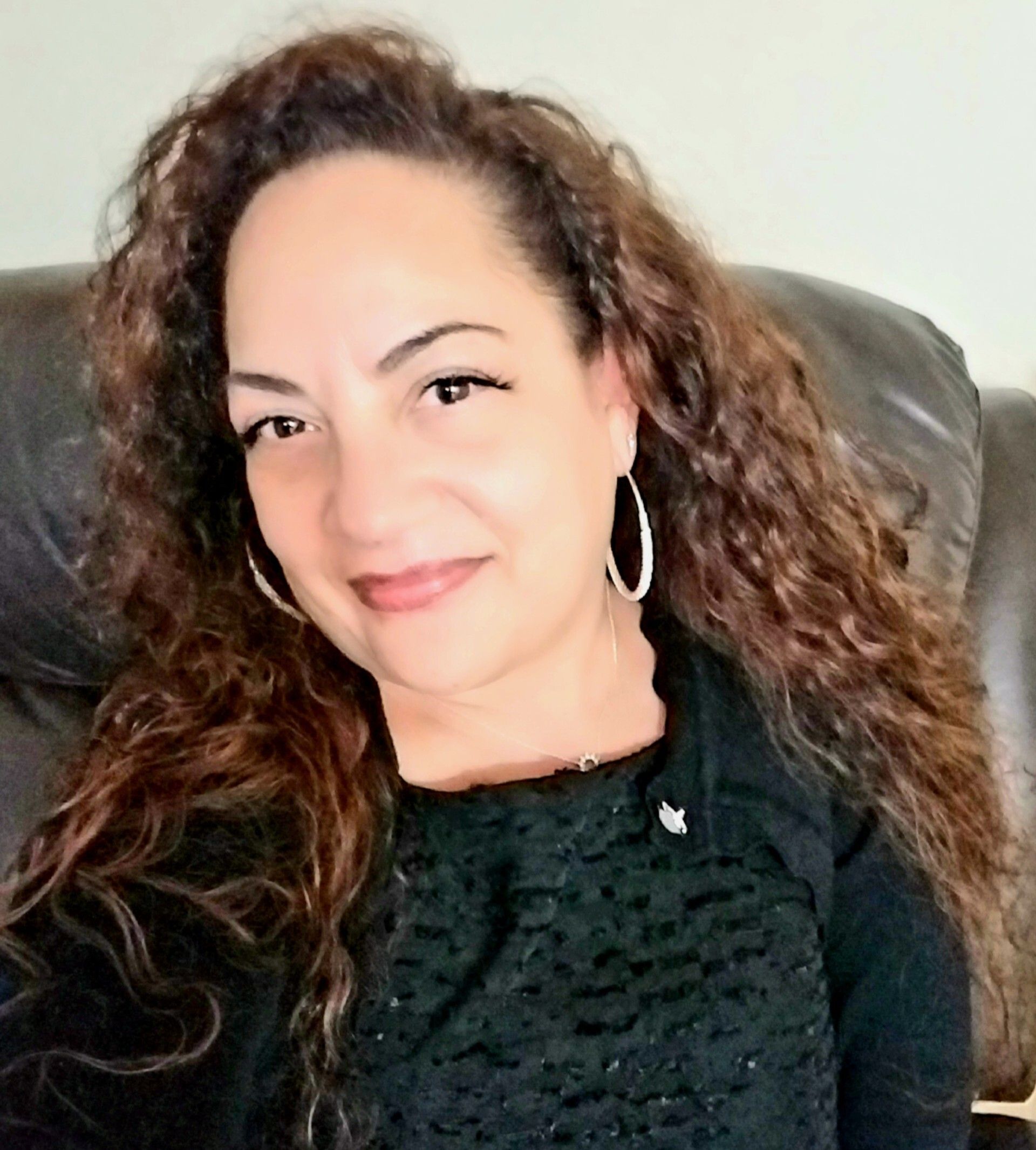 Woman wearing glasses and a stethoscope, smiling, in a white lab coat.