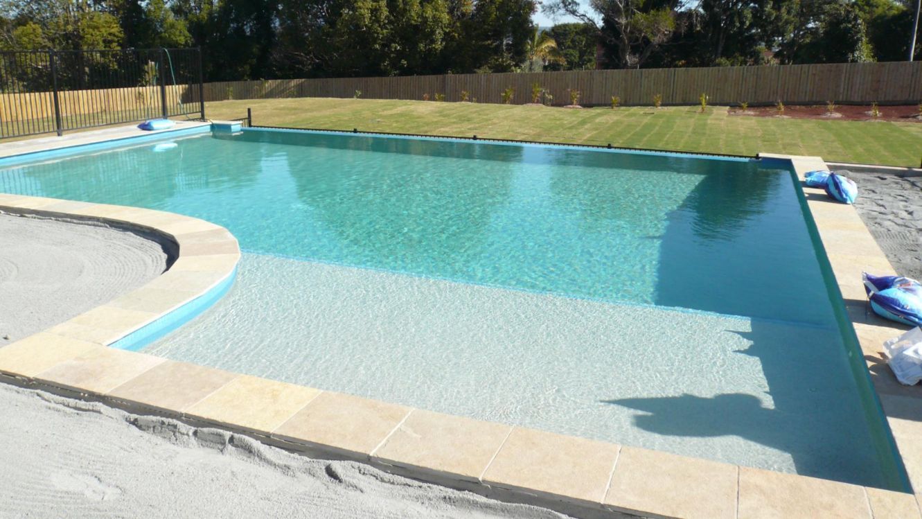 Swimming pool with shallow end, steps, and turquoise water. Lawn and fence in the background. — Banora Pools in Murwillumbah, NSW