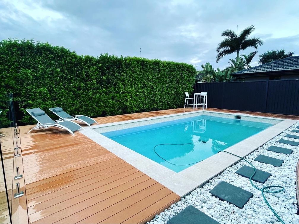 Poolside Scene With Lounge Chairs, a Pool, Wooden Deck, and Manicured Hedges — Banora Pools in Tweed Heads South, NSW