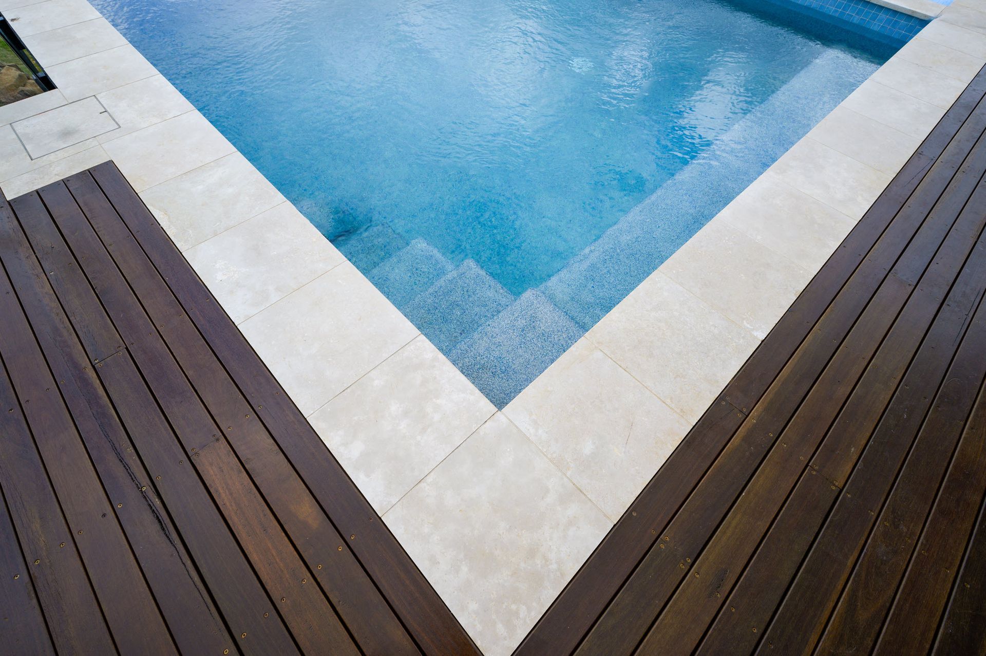 Pool with blue water, white tile surround, and dark wood decking.