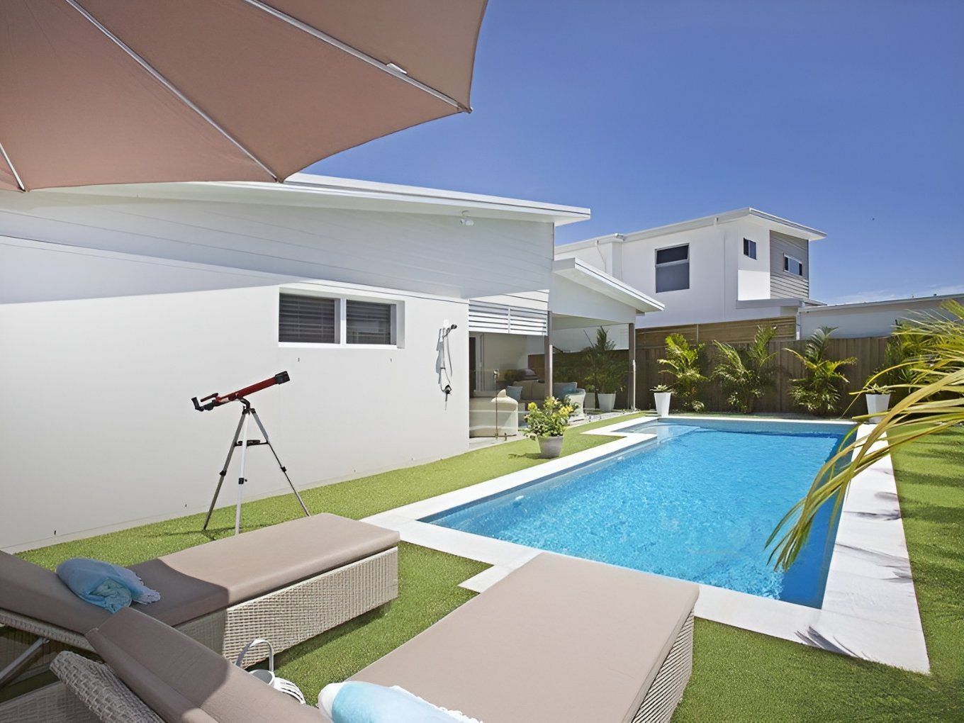 Backyard With a Rectangular Pool, Lounge Chairs, and White Buildings — Banora Pools in Mullumbimby, NSW