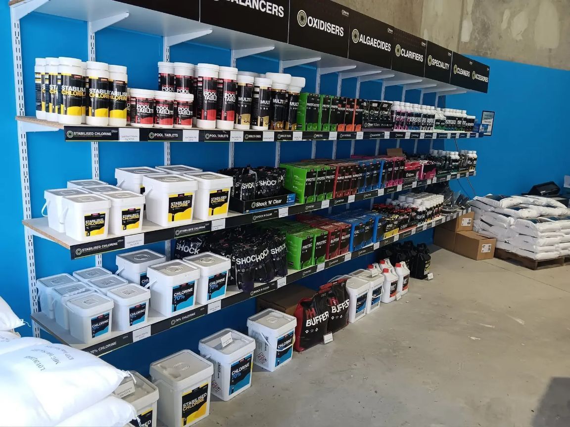 Shelves Stocked With Pool Supplies in a Store With Blue Walls, White Shelves, and Grey Floors — Banora Pools in Mullumbimby, NSW