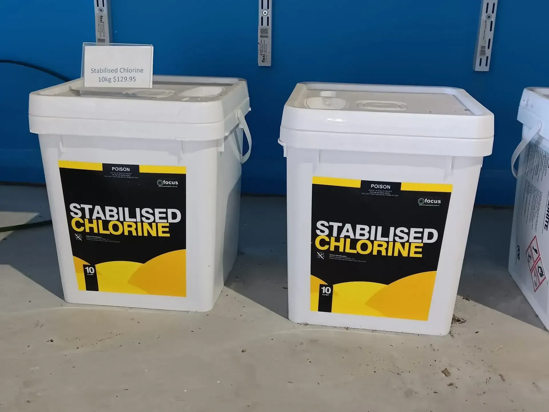 Two White Buckets Labeled Stabilised Chlorine on a Shelf, Against a Blue Wall — Banora Pools in Kingscliff, NSW