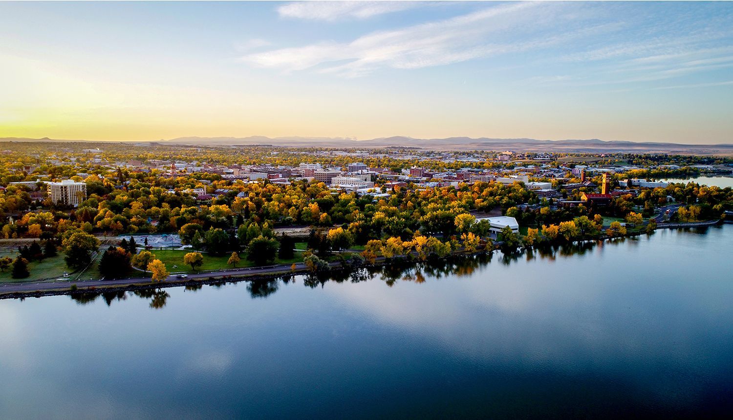 Aerial view of Great Falls, Montana at sunset featuring message We Live Here. We Work Here. We Love 