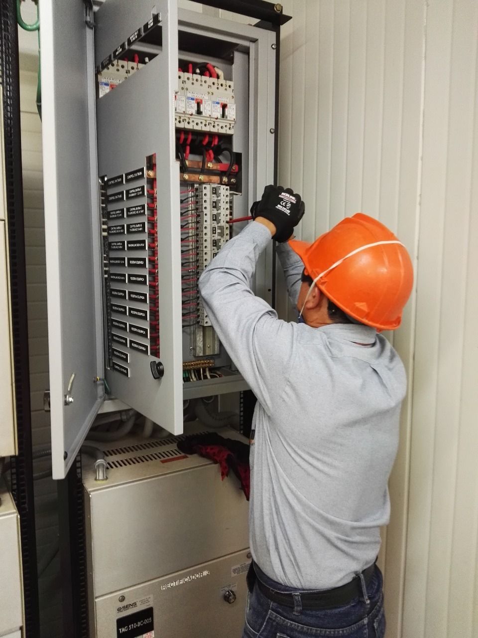 Panel de control eléctrico naranja con varios componentes, cables y disyuntores.