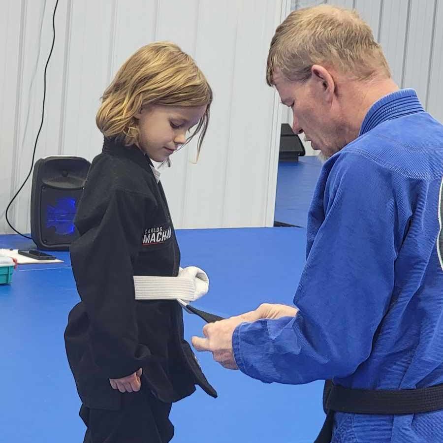 A man and a little girl are standing on a blue mat.