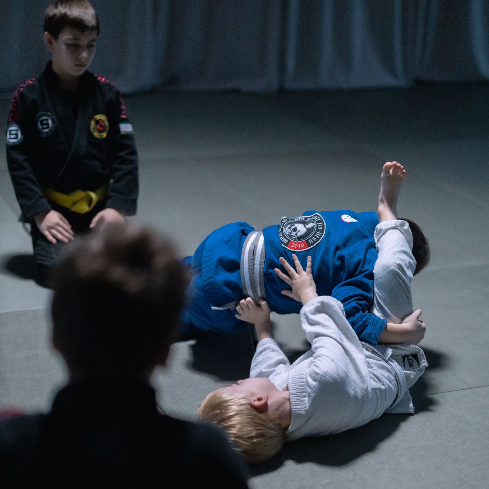 Two young boys are practicing martial arts in a dark room.