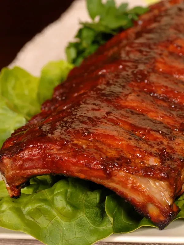 A close up of a piece of meat on a plate with lettuce.