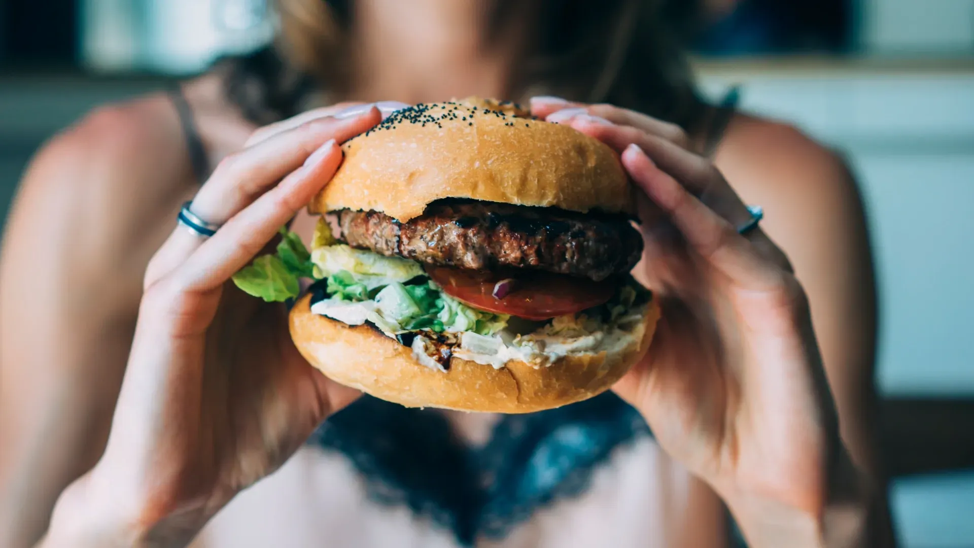 A woman is holding a hamburger in her hands.