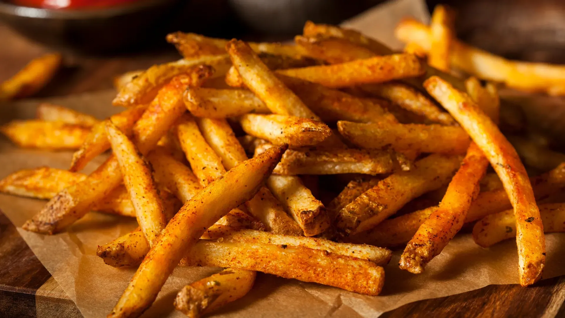 A pile of french fries sitting on top of a wooden table.