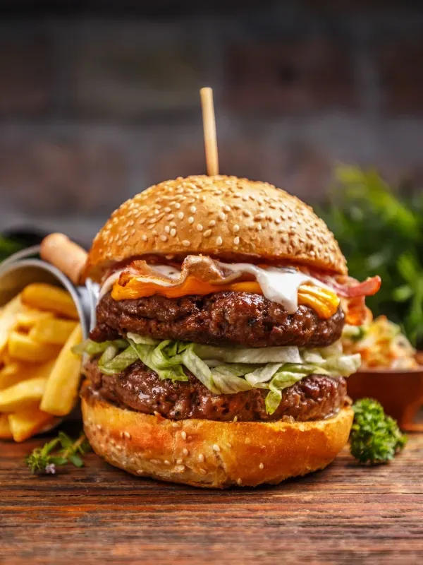 A close up of a hamburger and french fries on a wooden table.