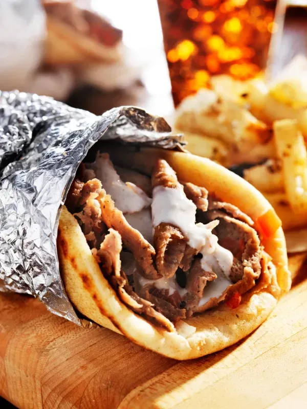 A delectable Gyro wrap filled with seasoned meat, fresh vegetables, and sauce, epitomizing Chicken Shack's tasty gyro wraps.