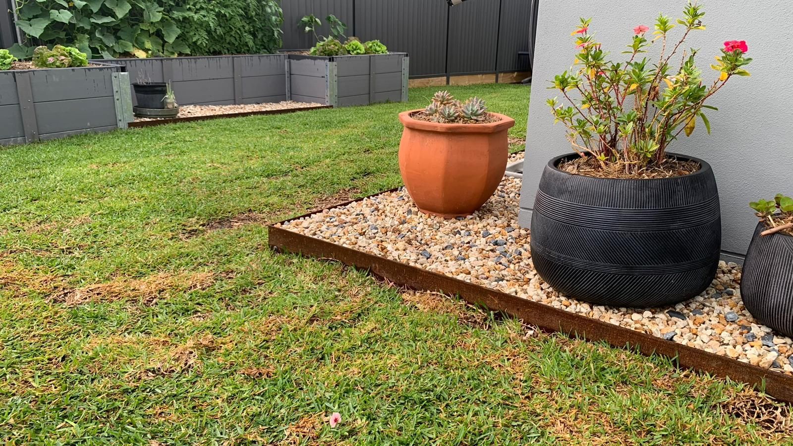 Garden area with planters, gravel path, and green grass.