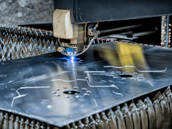 An industrial laser cutter precisely slices through a metal sheet on a manufacturing table.