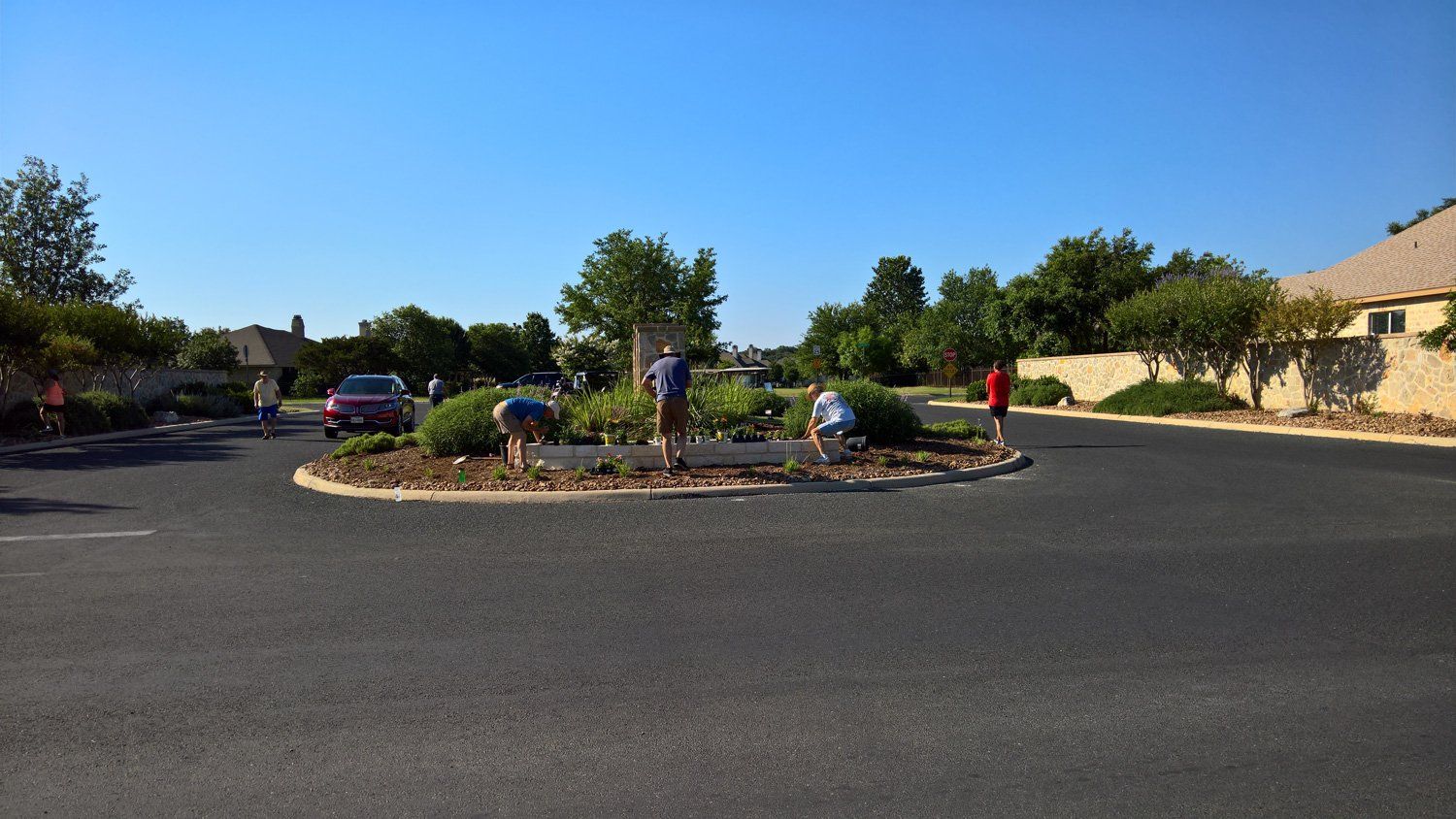 A group of people are working on a garden in a parking lot.