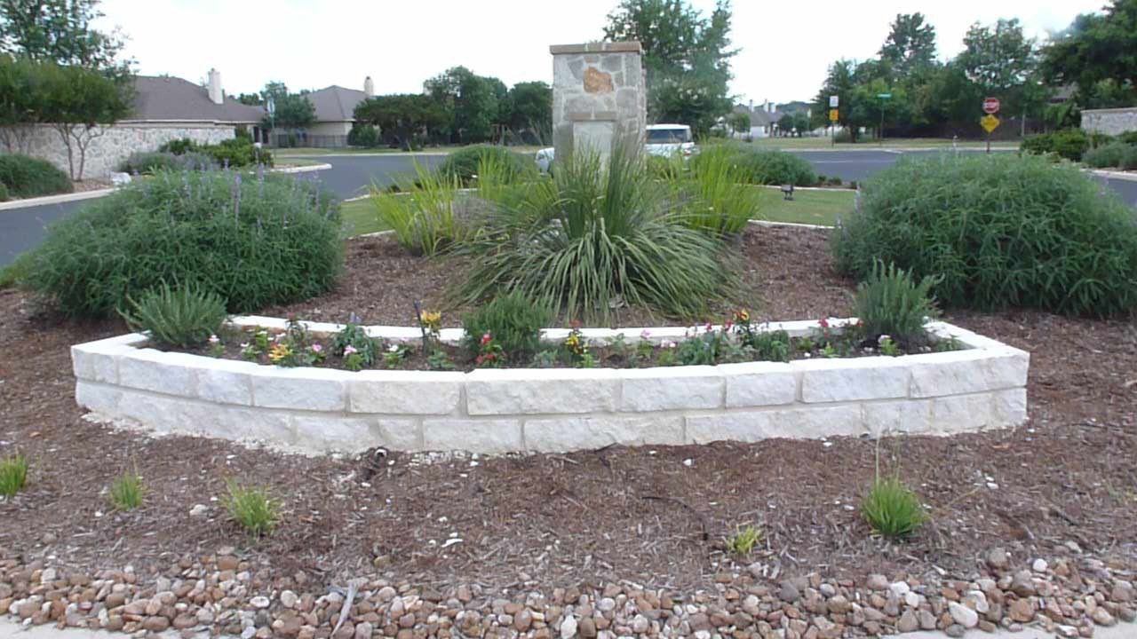 A brick planter in the middle of a garden