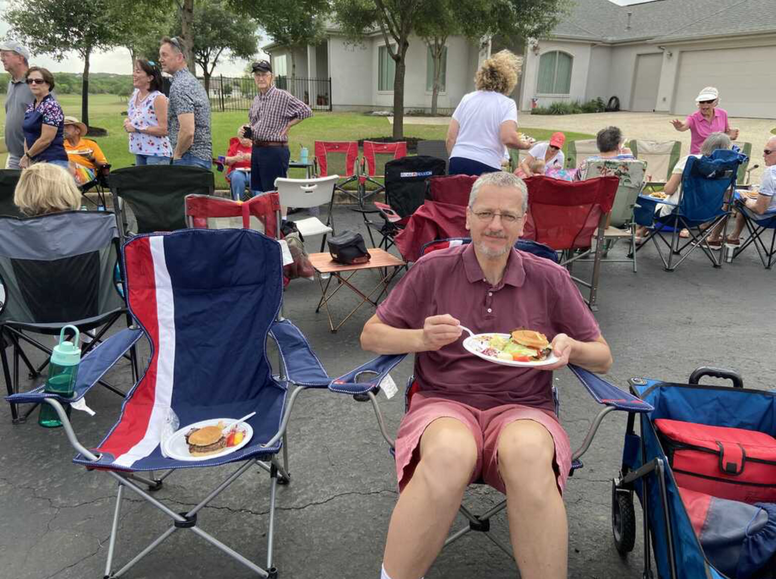 A man is sitting in a chair with a plate of food in his hand.