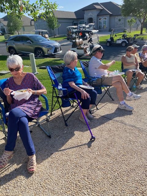 A group of people are sitting in chairs outside eating