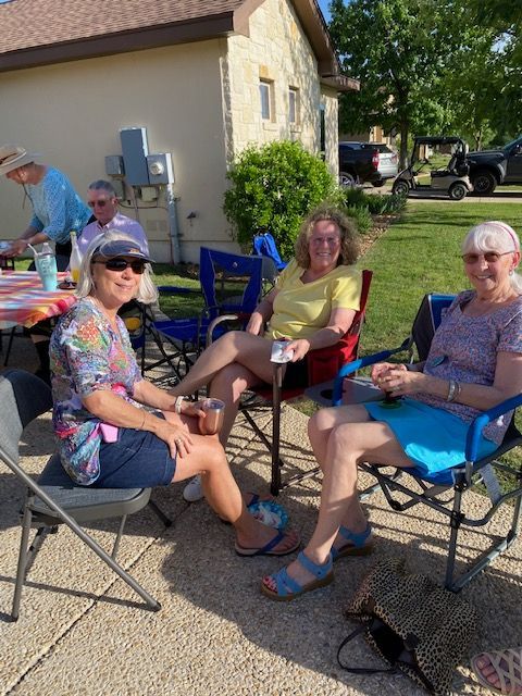 A group of people are sitting in folding chairs outside of a house.