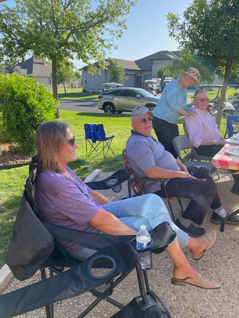 A group of people are sitting in chairs in a park.