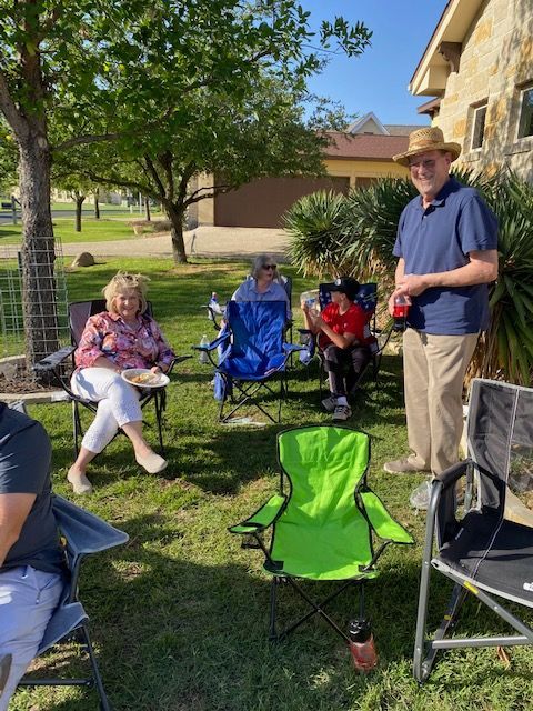 A group of people are sitting in chairs in a yard.