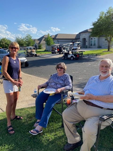 A group of people are sitting in chairs in front of a golf cart.