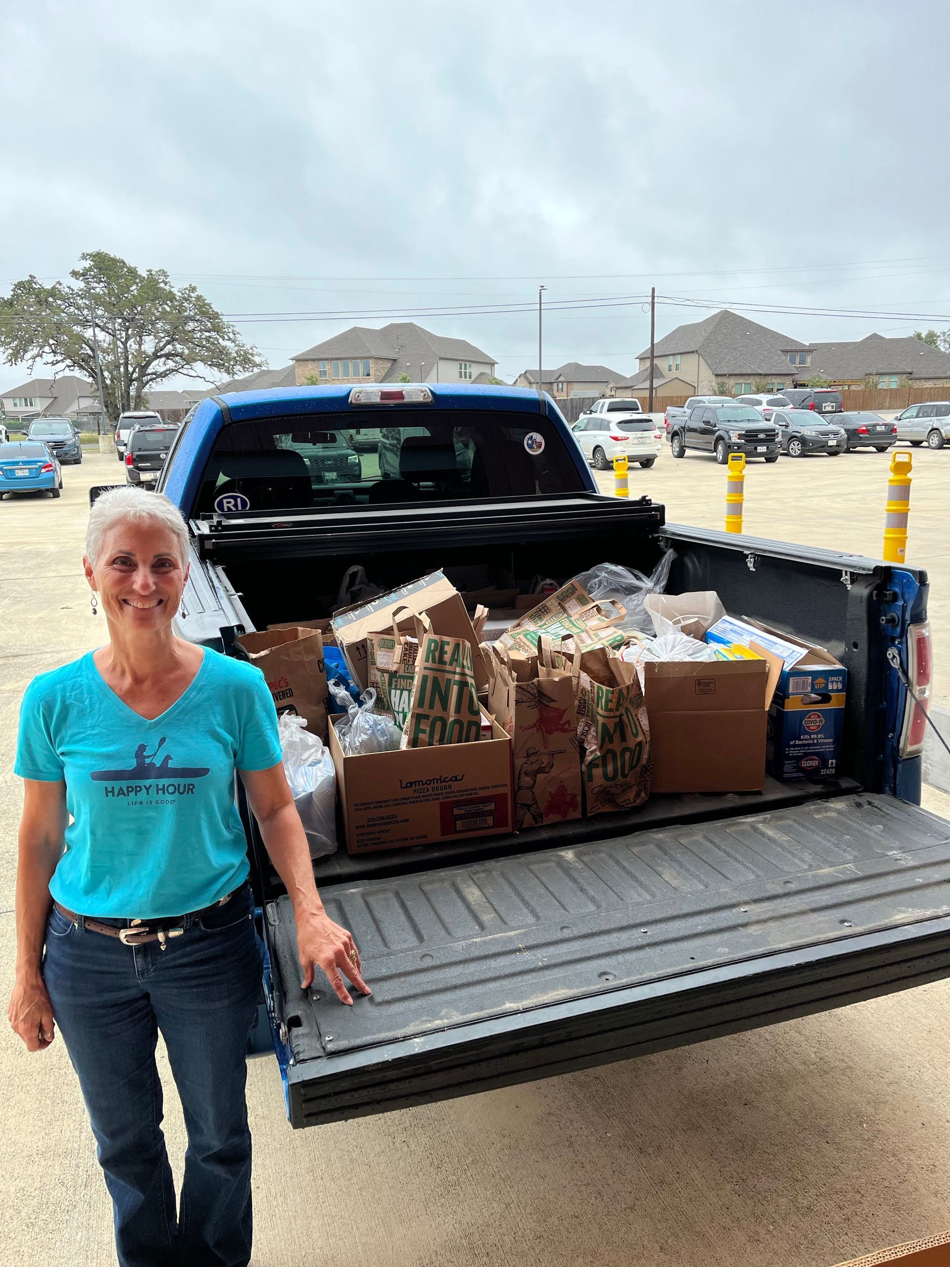 A woman is standing in front of a truck filled with boxes and bags.