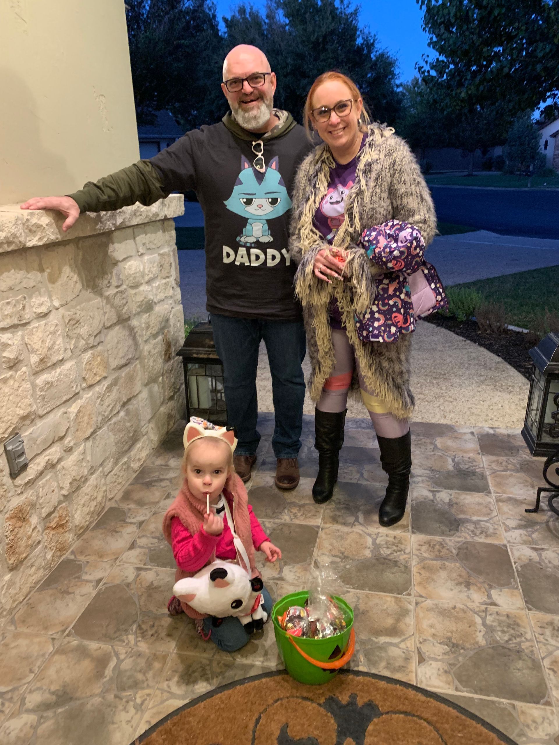 A man and woman are standing next to a little girl on a porch.
