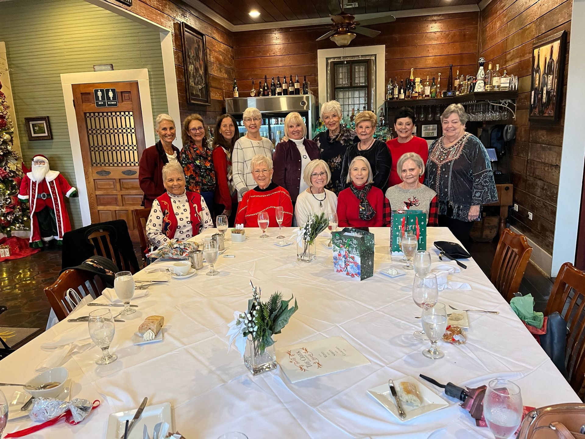 A group of older women are sitting around a long table.