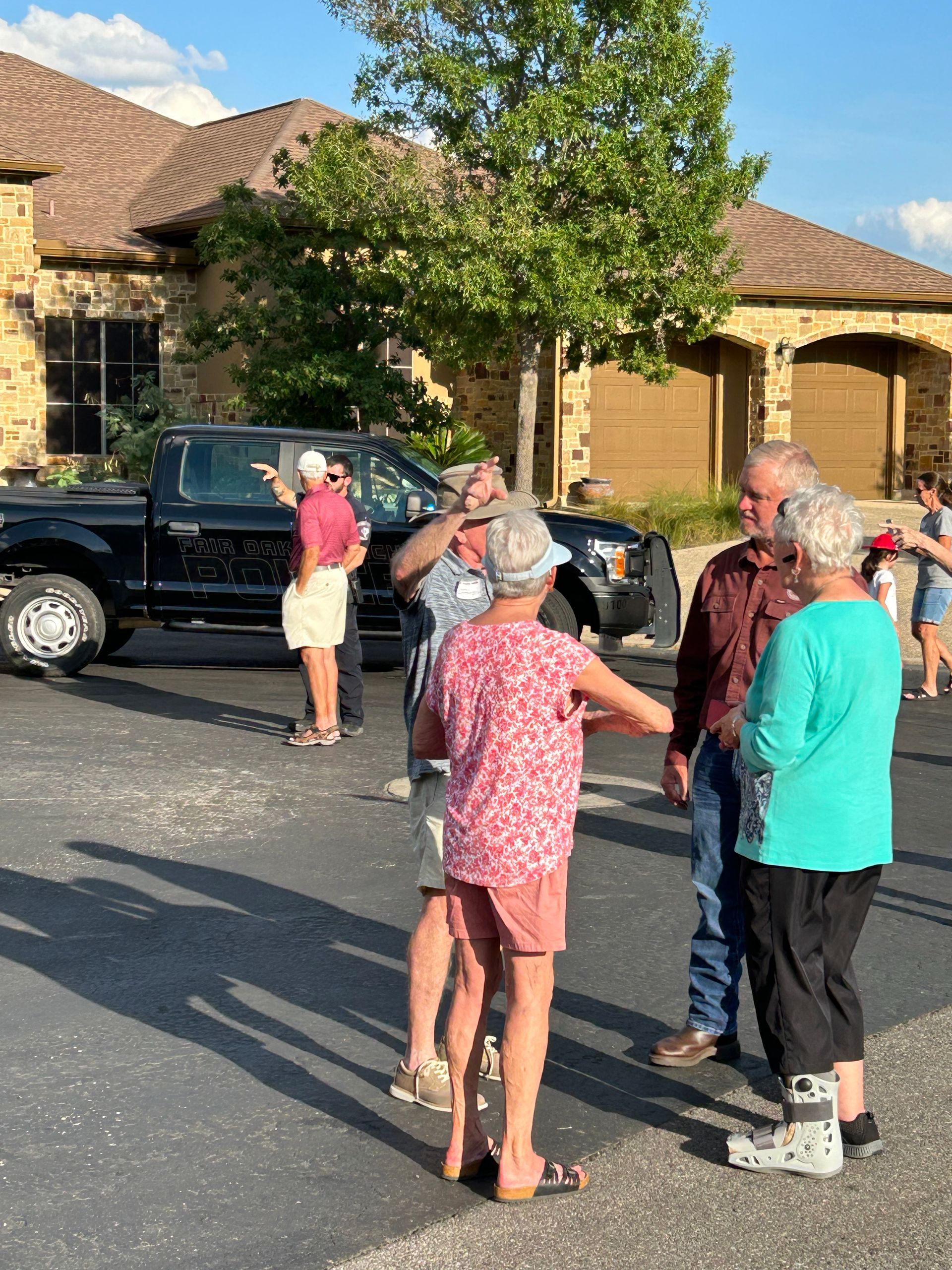 A group of people are standing in a parking lot in front of a house.