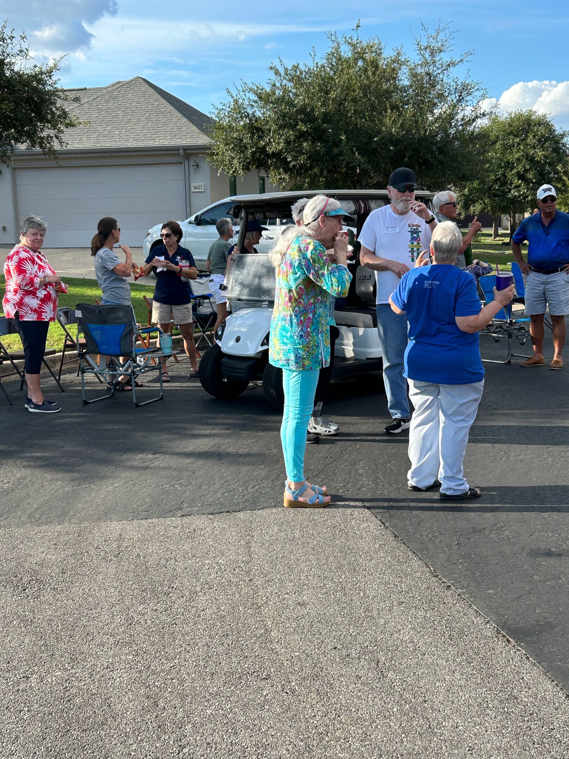 A group of people are standing in front of a golf cart.