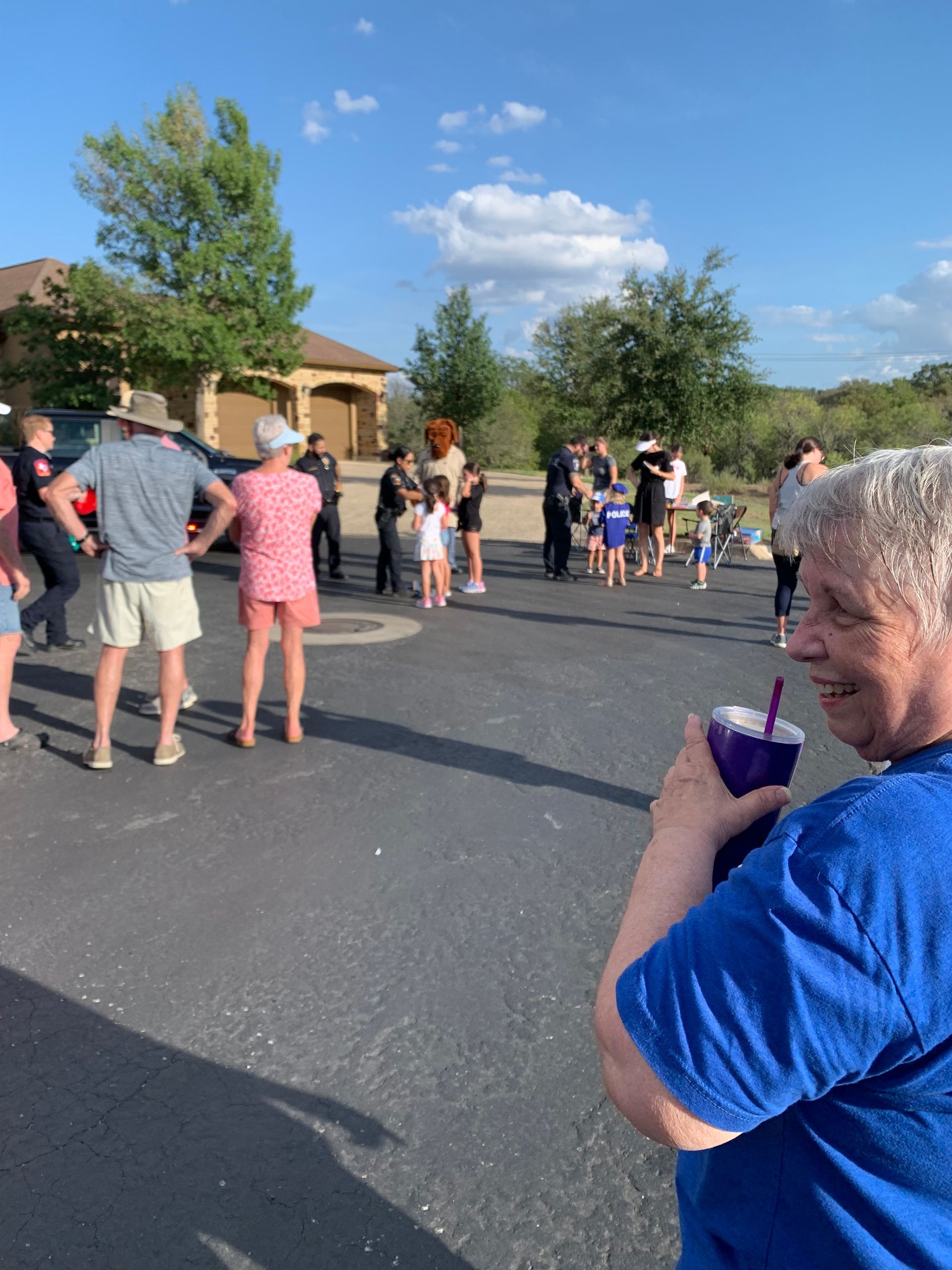 A man in a blue shirt is drinking from a purple cup with a straw.
