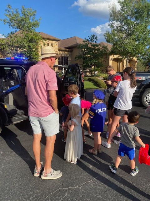 A group of children are standing in front of a police car