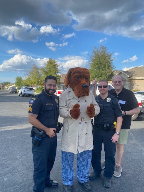 A group of police officers standing next to a mascot in a trench coat.