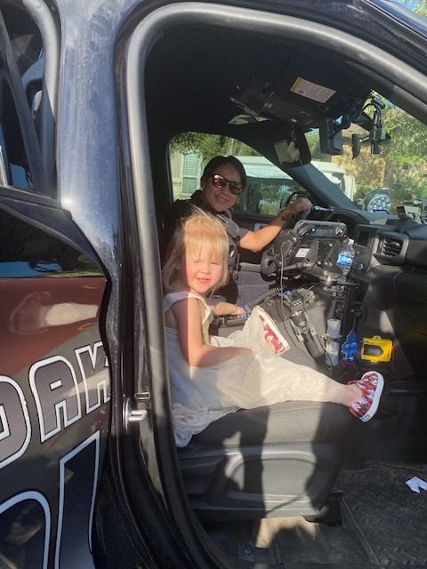 A little girl is sitting in the back seat of a police car