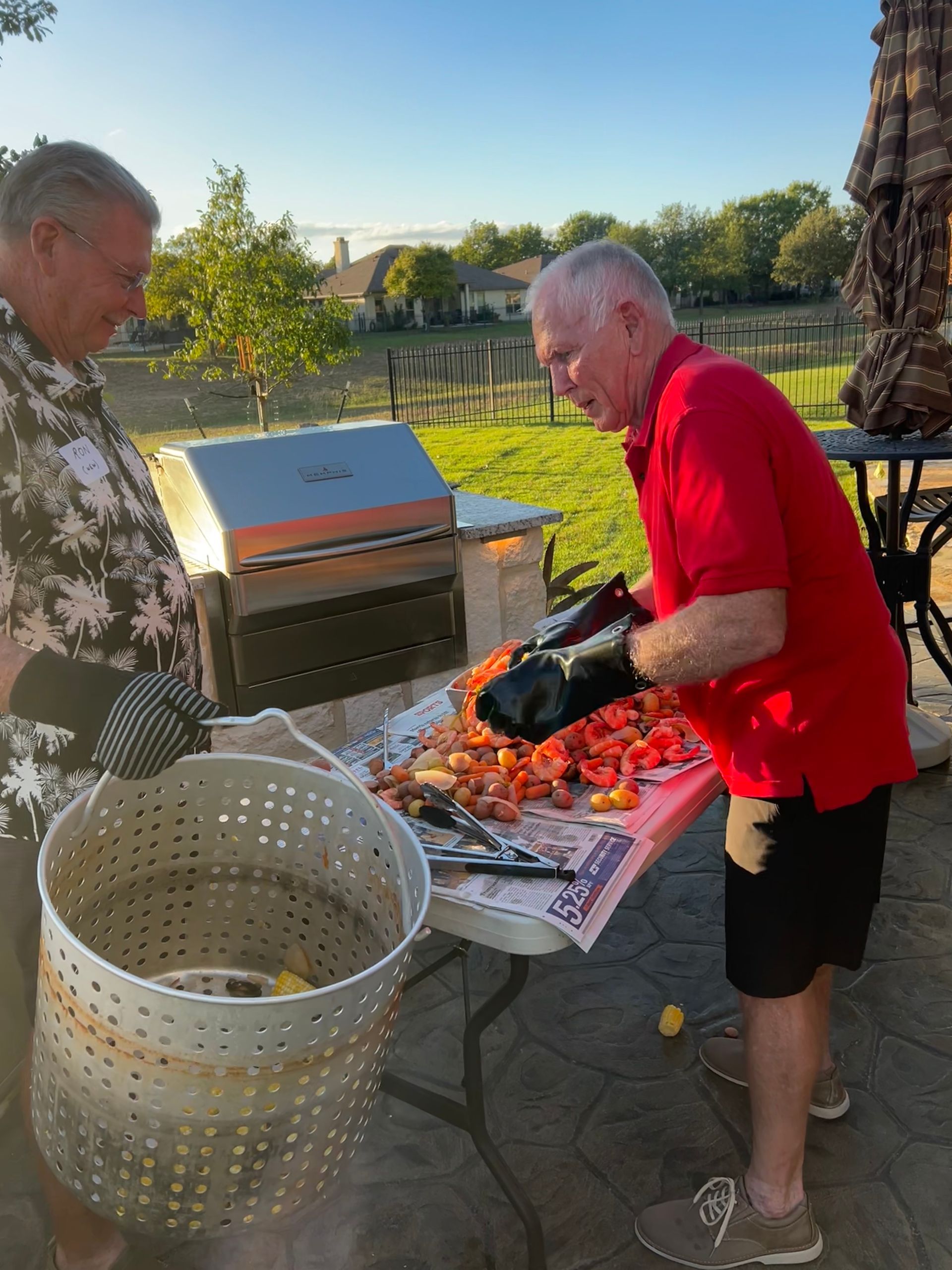 A man in a red shirt is standing next to a table with shrimp on it.