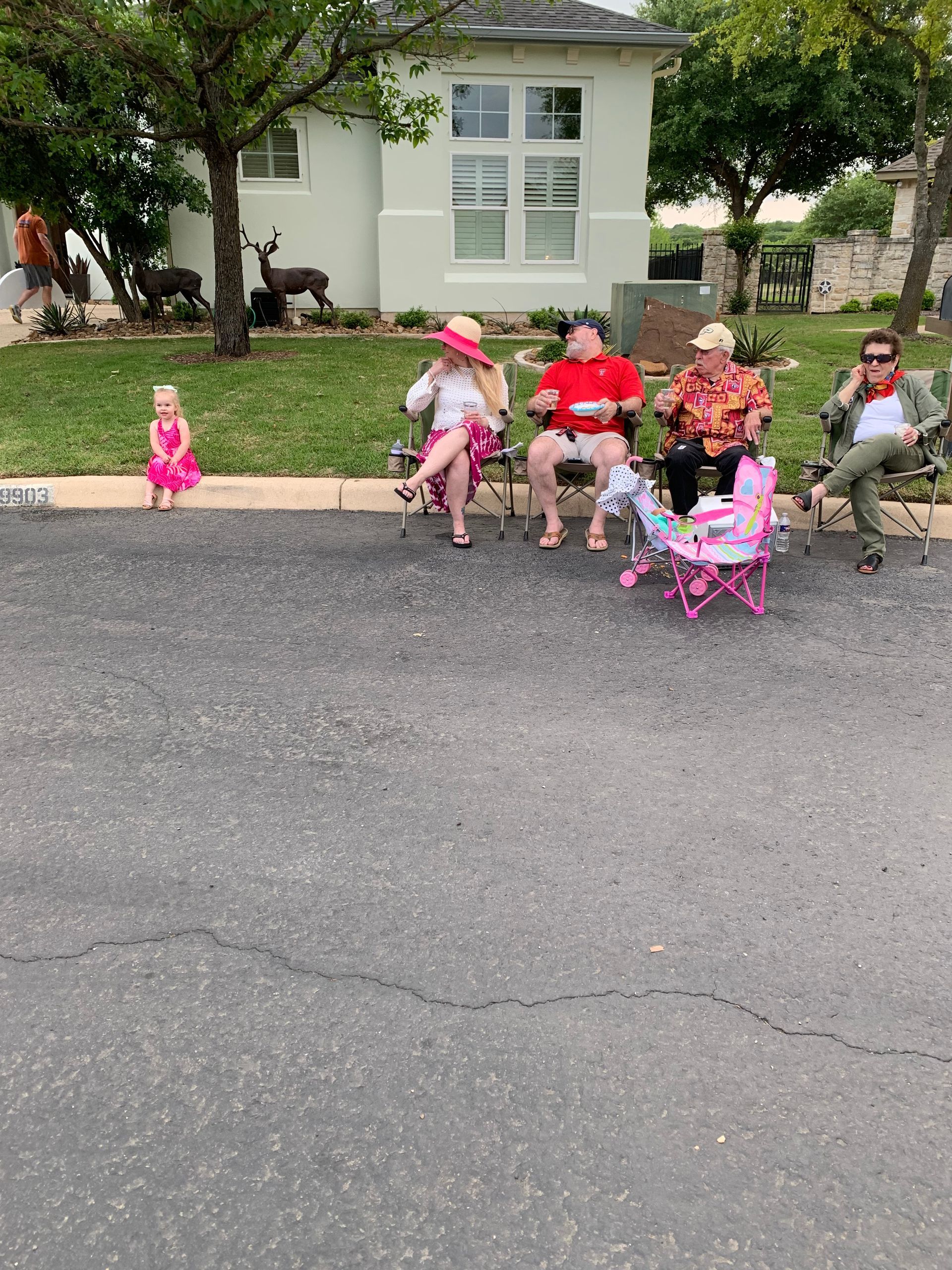 A group of people are sitting on a bench in a parking lot.