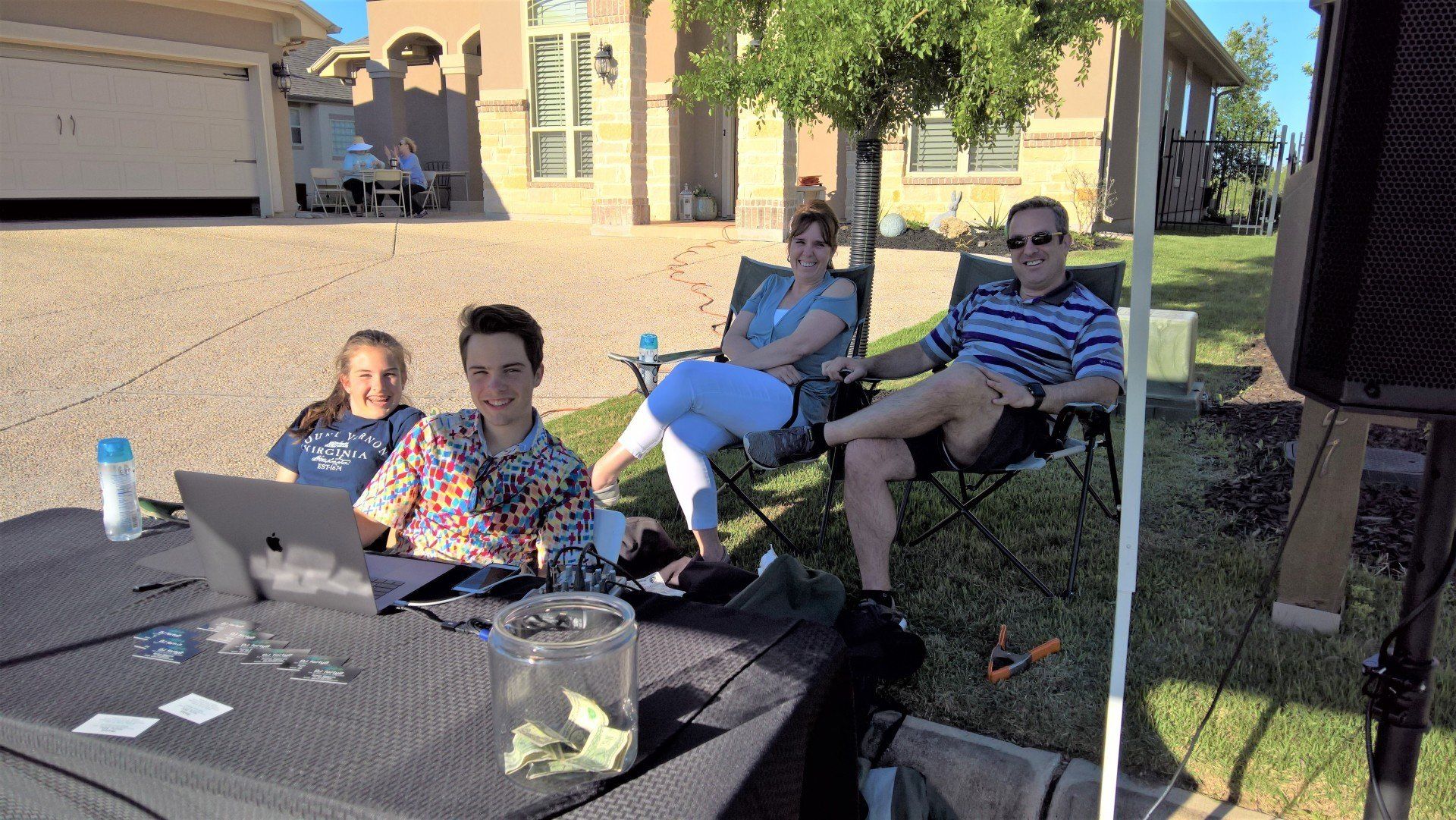 A group of people are sitting around a table in front of a house.