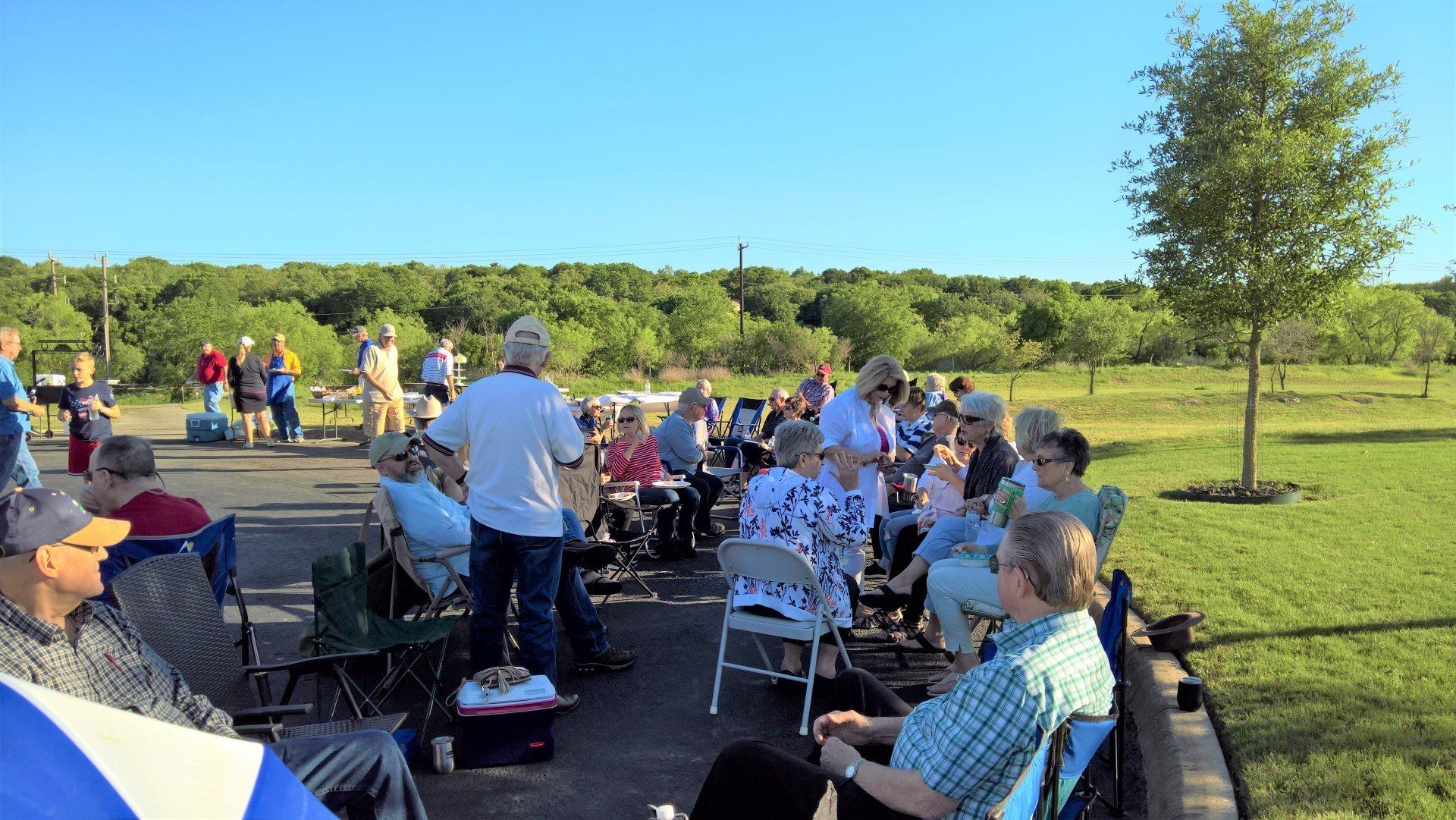 A group of people are sitting in chairs in a park