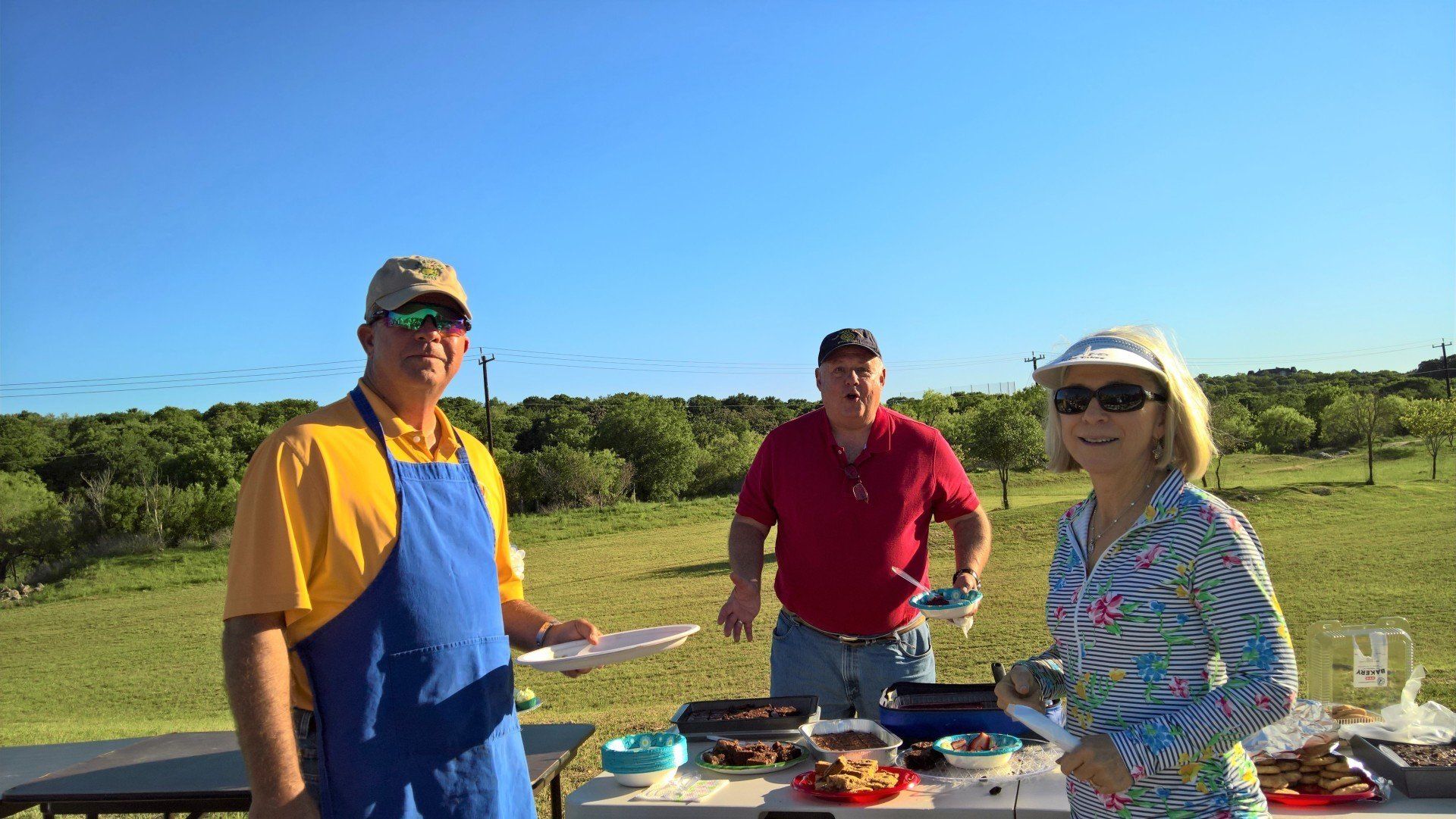 A group of people are standing around a table in a field.