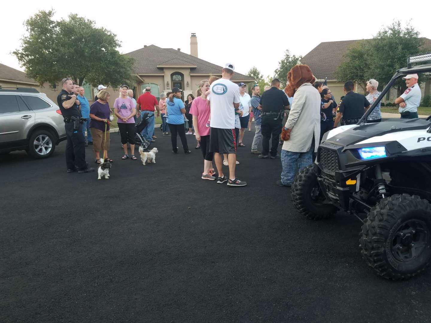 A group of people are standing in a parking lot in front of a polaris atv