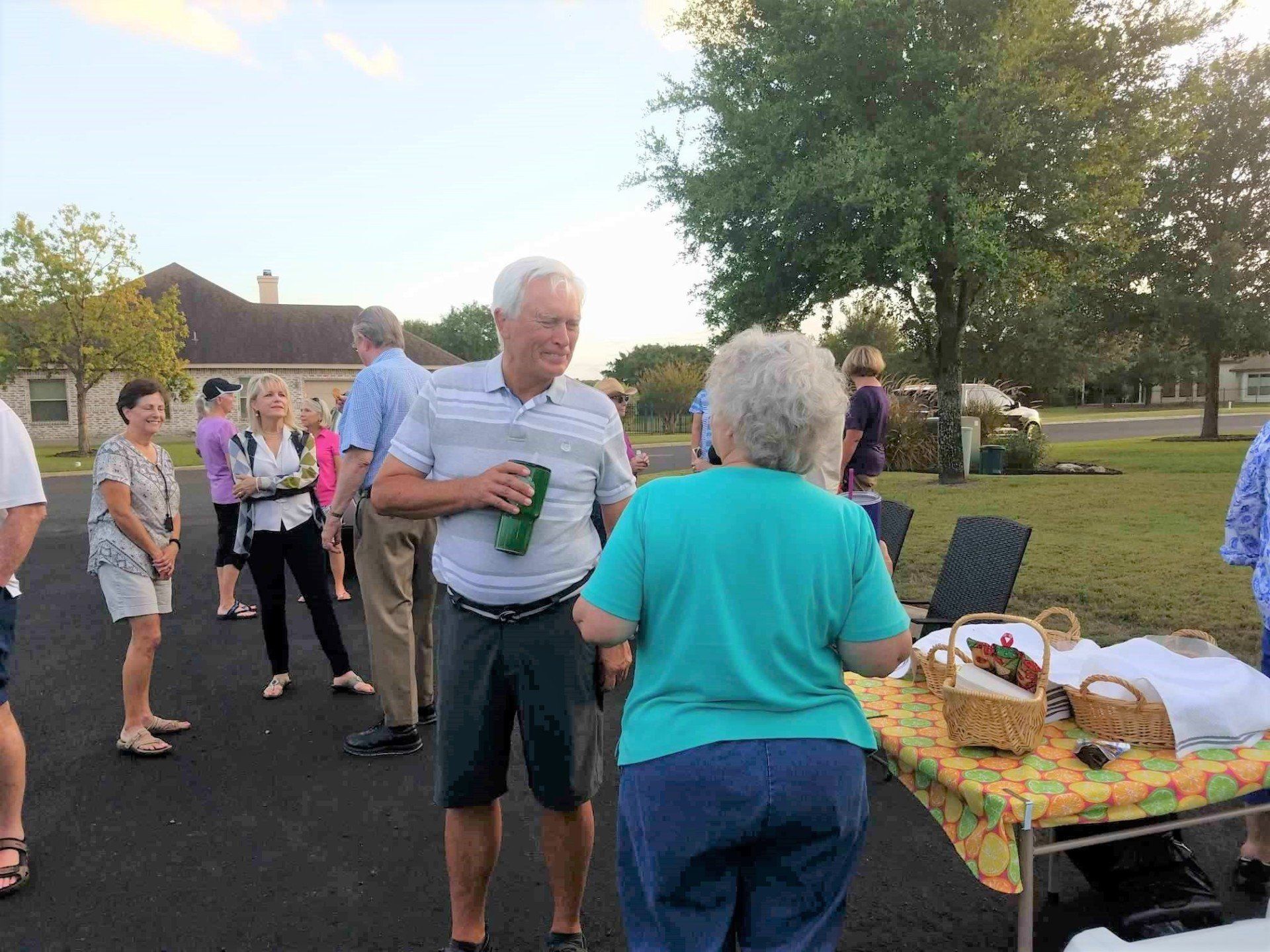 A group of people are standing in a parking lot talking to each other.