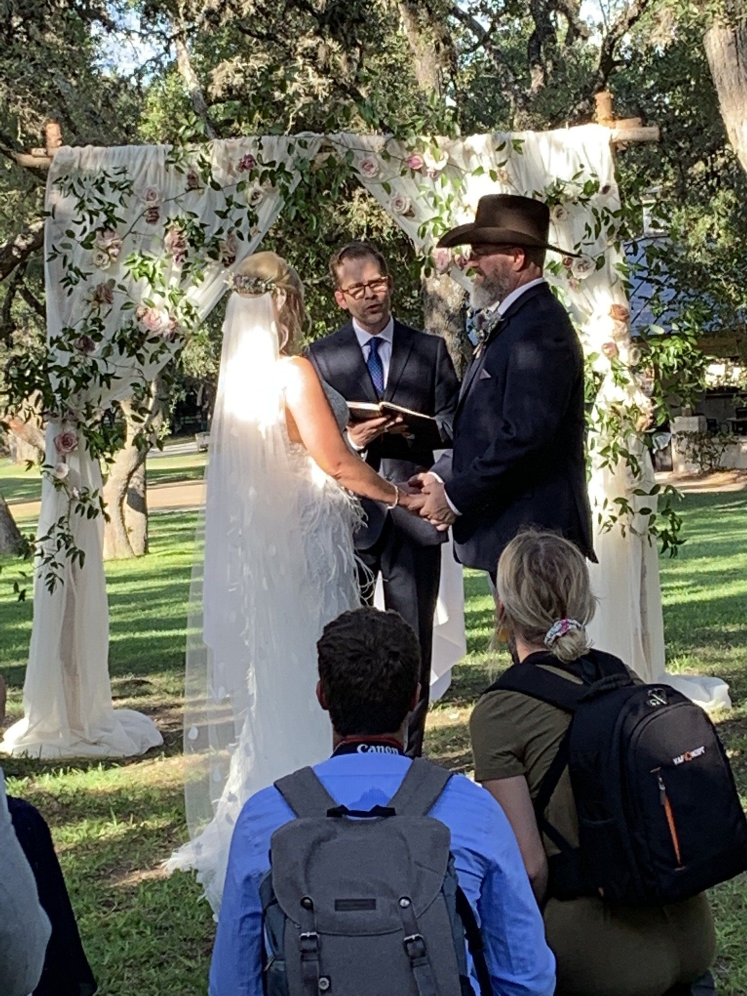 A bride and groom are getting married in front of a crowd of people.