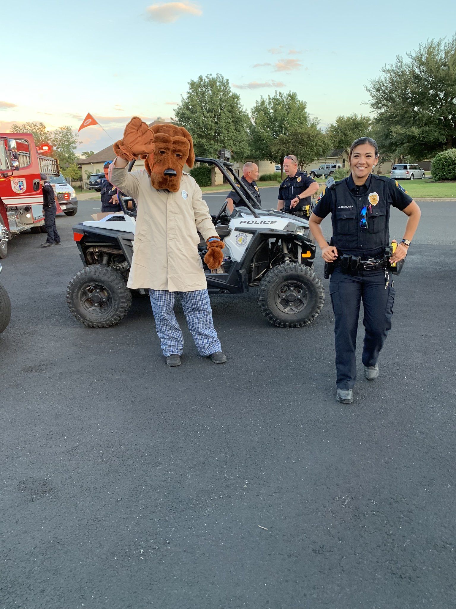 A lion mascot is standing next to a police officer in a parking lot.