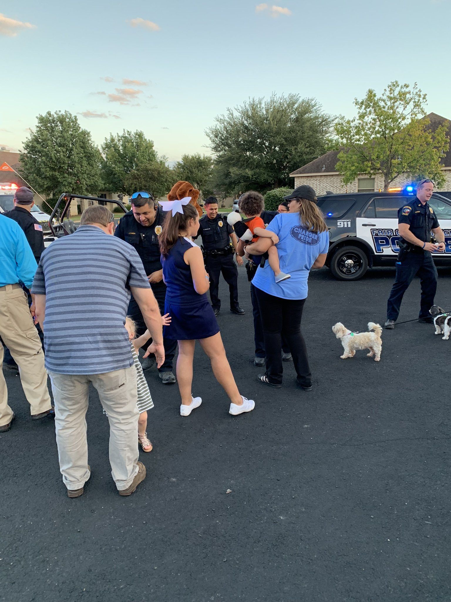 A group of people are standing in a parking lot next to a police car.