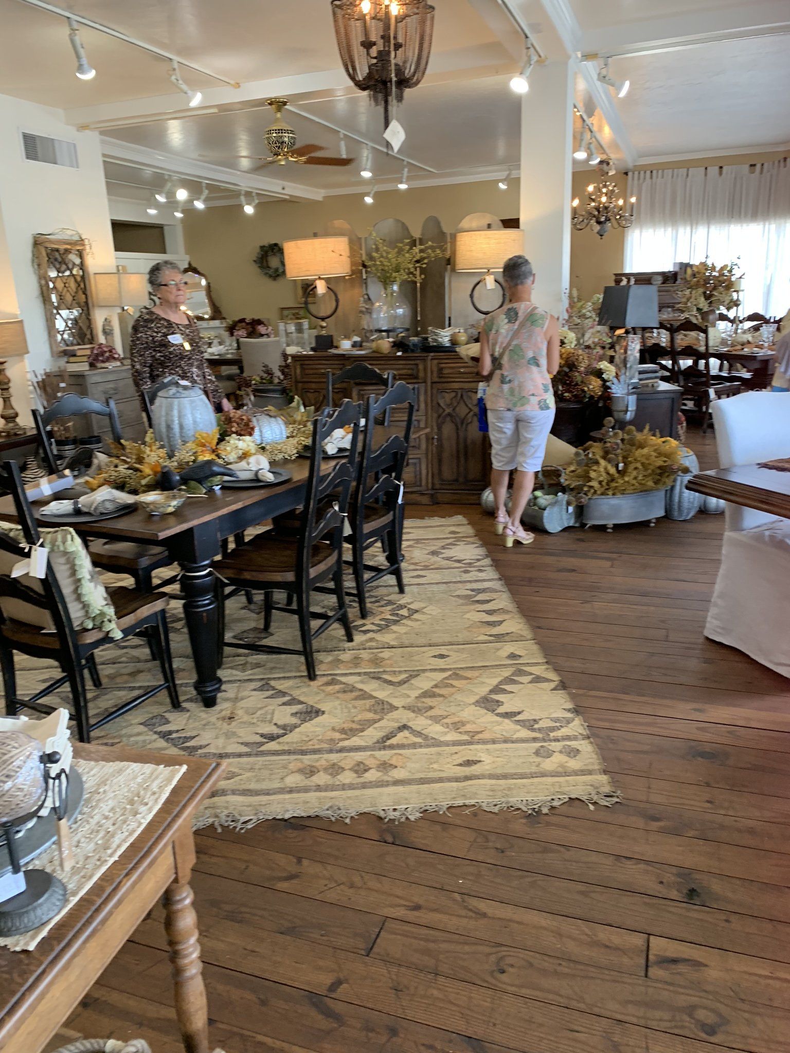A woman is standing in a room with tables and chairs.